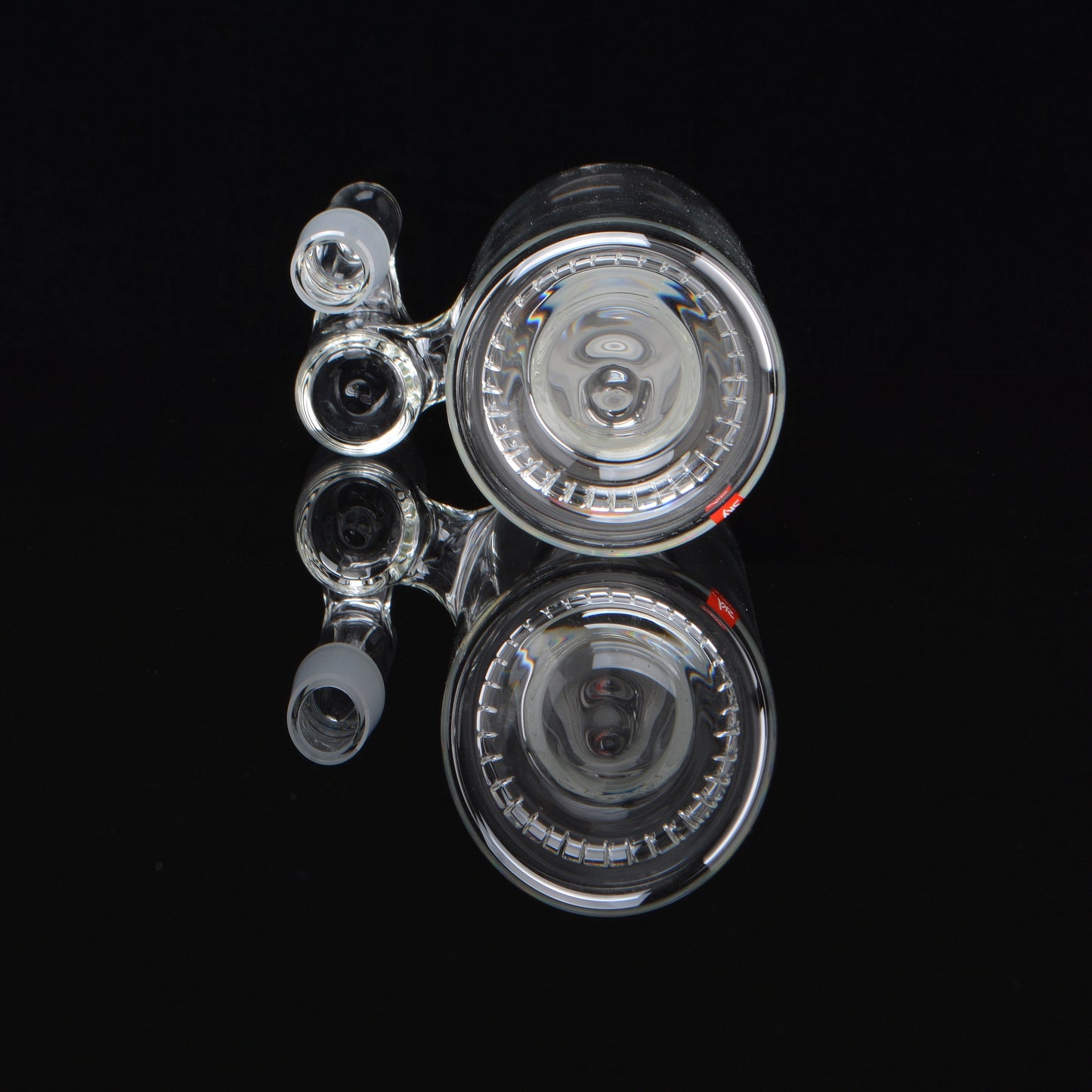 Splashcatcher for a bong laying on its side rotated 90 degrees on a black background
