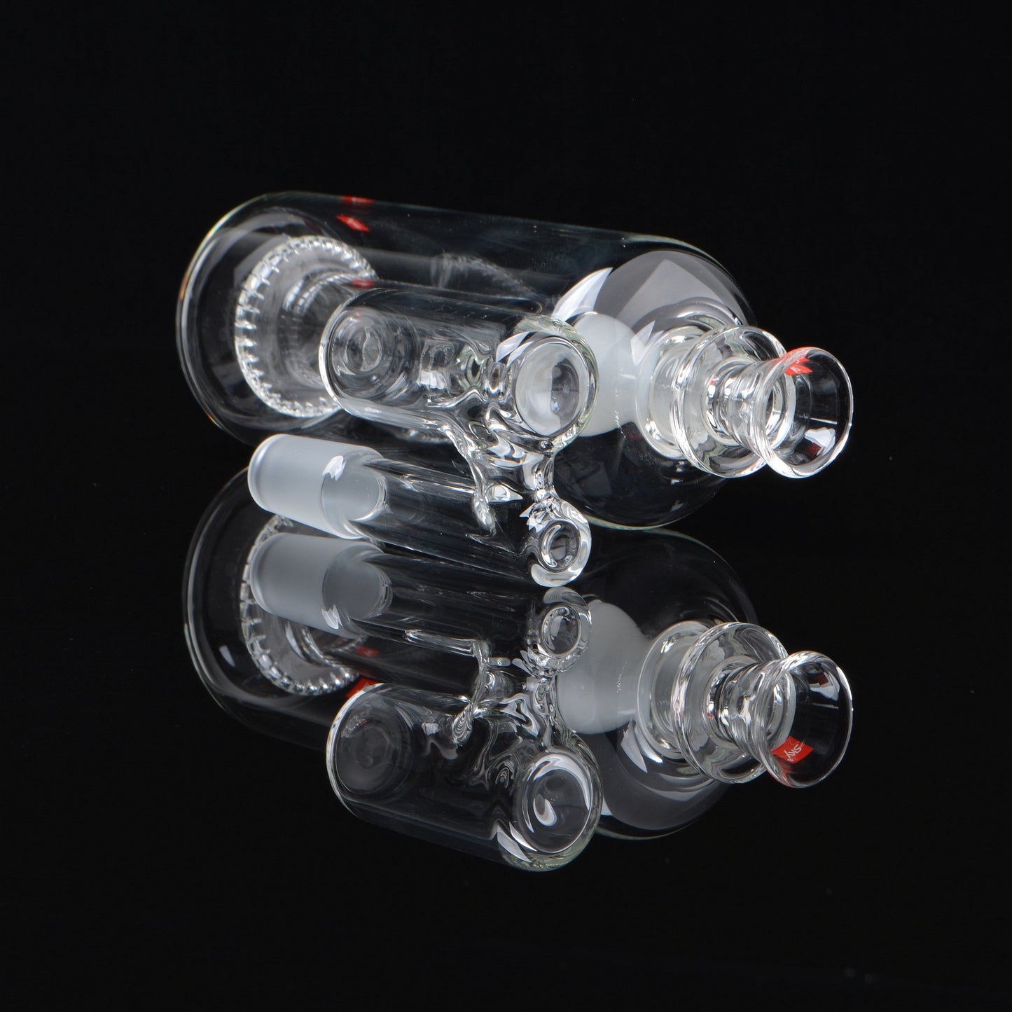Splashcatcher for a bong laying on its side rotated 45 degrees on a black background